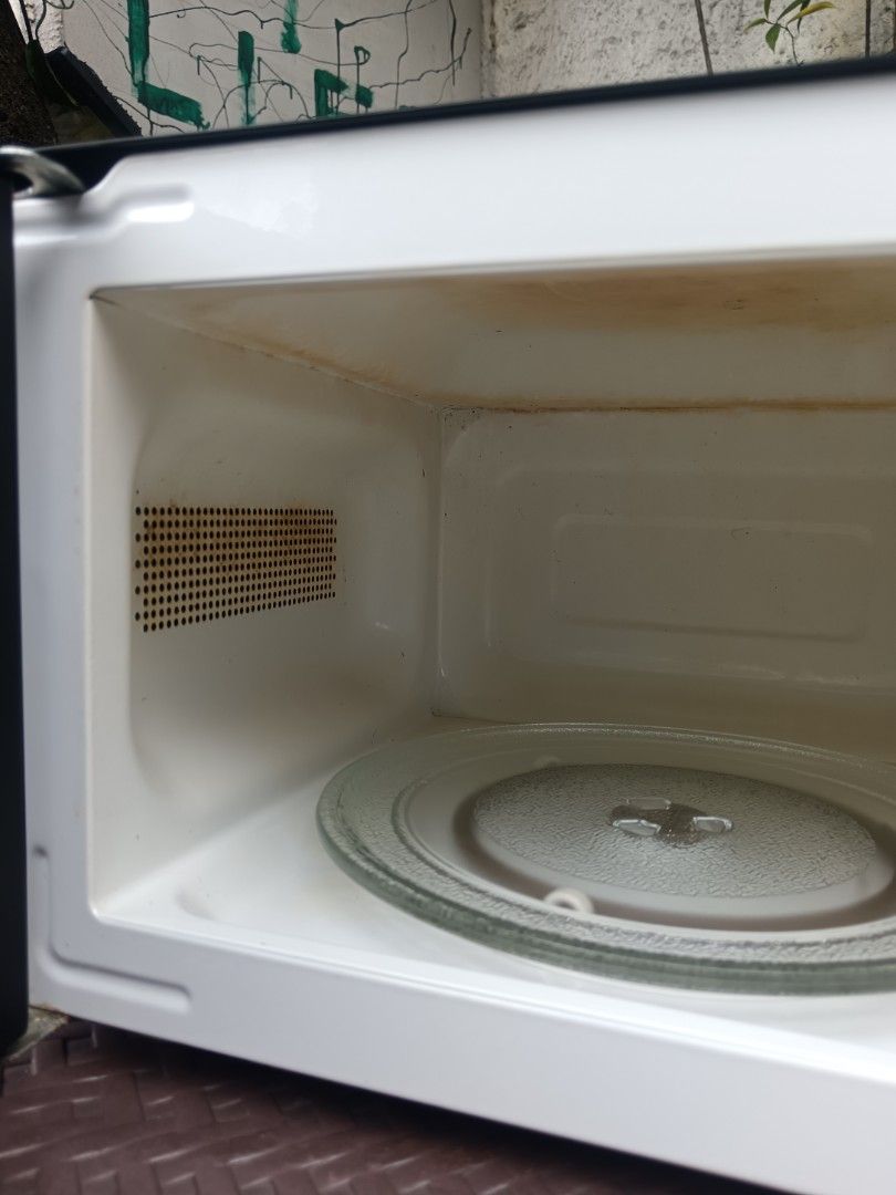 American Home black microwave oven (Category: Ovens & Toasters) located in Pasig City. Submitted by richs.lusr (Listing ID 1469405235, Image 3). Description: - Brand: American Home - Color: Classic Black - Type: Standard countertop microwave oven - Controls: Easy-to-use dual knobs for power levels and timer - Included: Glass turntable plate inside - Flaws: Minor food stain spots near the side vent and upper panel (does not affect performance) - C