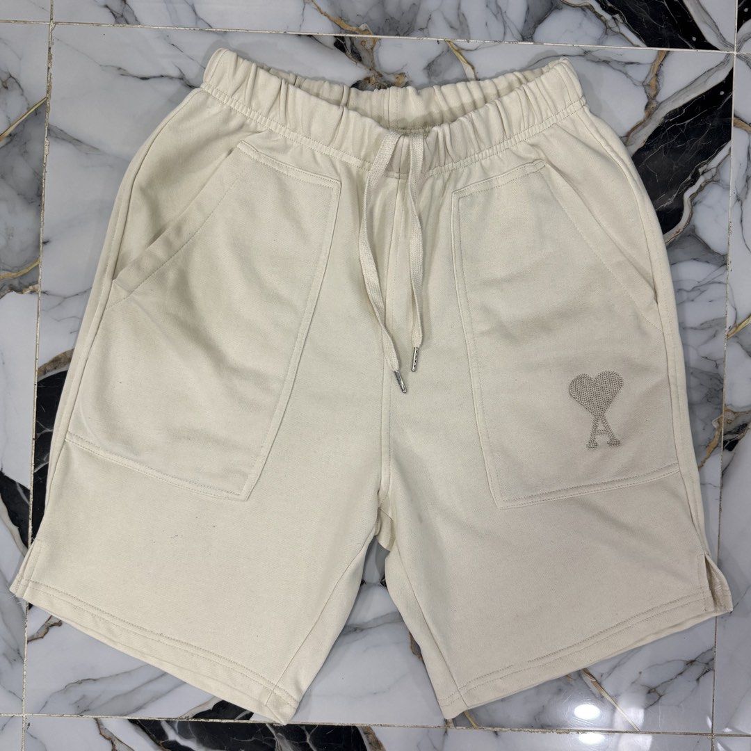 Ami Paris Cream Sweatshorts Size M (Category: Shorts) located in Manila. Submitted by fastflip.ph (Listing ID 1469429506, Image 1). Description: - Brand: Ami Alexandre Mattiussi - Size: M - Color: Cream - Material: Soft cotton fleece - Waist: Elastic with drawstring - Details: Large front patch pockets, rhinestone heart logo near left hem, side slits at bottom.