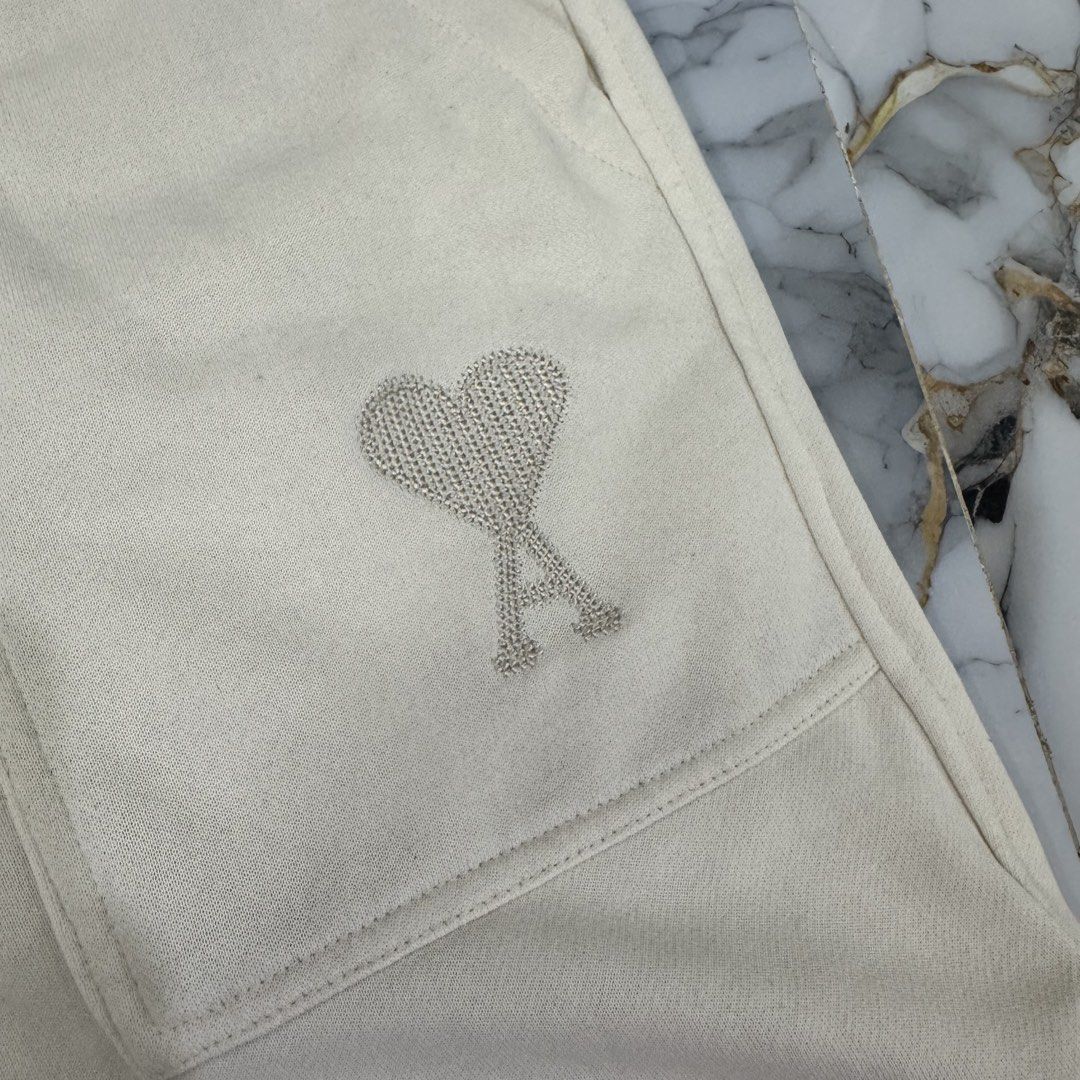 Ami Paris Cream Sweatshorts Size M (Category: Shorts) located in Manila. Submitted by fastflip.ph (Listing ID 1469429506, Image 2). Description: - Brand: Ami Alexandre Mattiussi - Size: M - Color: Cream - Material: Soft cotton fleece - Waist: Elastic with drawstring - Details: Large front patch pockets, rhinestone heart logo near left hem, side slits at bottom.
