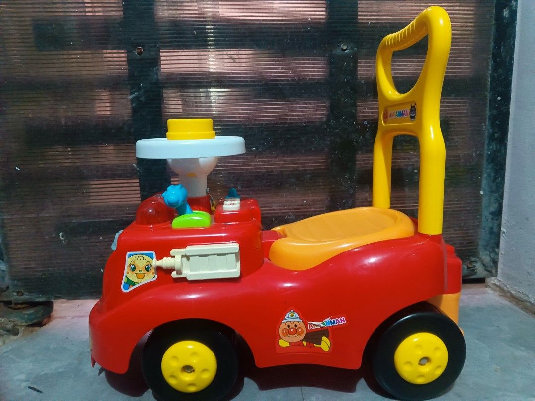 Anpanman Fire Engine Ride-on Push Toy (Category: Kids Toys) located in Manila. Submitted by mateochest99469 (Listing ID 1469482162, Image 3). Description: -Battery Operated Sounds - Authentic Anpanman fire engine push toy - Bright red design with yellow push handle and orange seat - Includes a steering wheel and back handle support for toddlers - Features fun character graphics on the front and sides - Built with sturdy black and yellow wheels - 