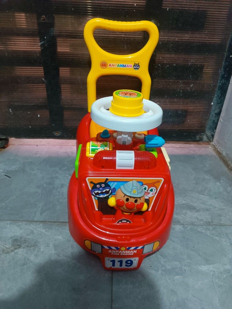 Anpanman Fire Engine Ride-on Push Toy (Category: Kids Toys) located in Manila. Submitted by mateochest99469 (Listing ID 1469482162, Image 1). Description: -Battery Operated Sounds - Authentic Anpanman fire engine push toy - Bright red design with yellow push handle and orange seat - Includes a steering wheel and back handle support for toddlers - Features fun character graphics on the front and sides - Built with sturdy black and yellow wheels - 