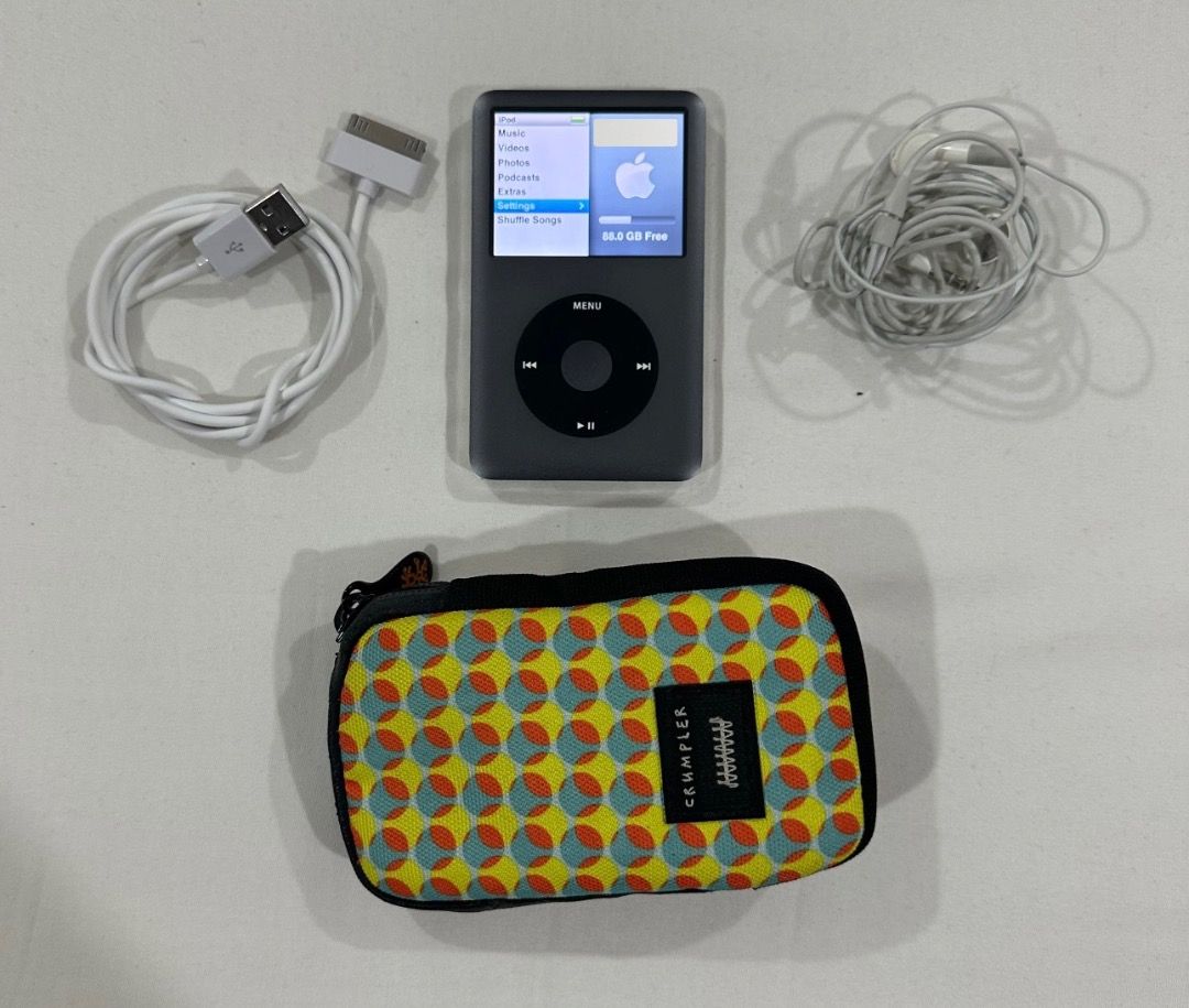 Apple iPod Classic 160GB with Case (Category: Portable Music Players) located in San Juan City. Submitted by looneybin559 (Listing ID 1469438313, Image 2). Description: - Model: Apple iPod Classic (160GB, Dark Grey Silver) - Condition: Fully working, screen turns on clearly, charges normally - Flaws: Minor scratches on the chrome back panel from normal use - Inclusions: 30-pin USB sync charging cable, wired Apple earphones, and a colourful patter