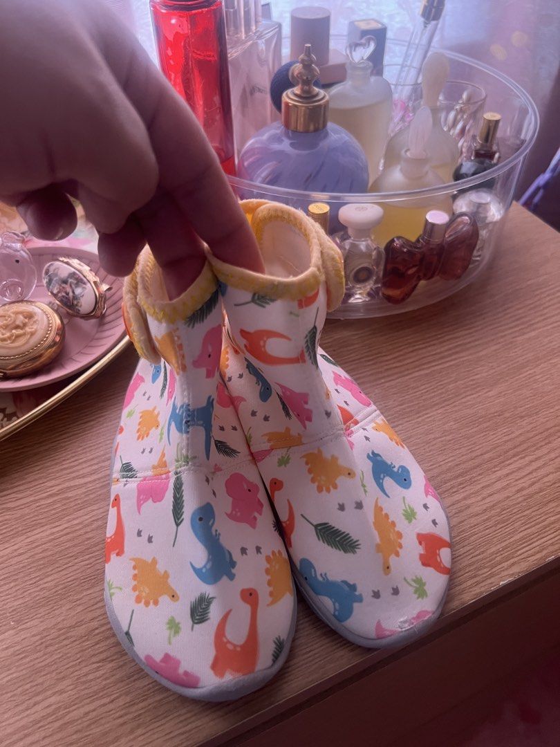 AQUA Booties Soft Sole Shoes (Category: Babies & Kids Fashion) located in Cebu City. Submitted by shofaholicz (Listing ID 1469457137, Image 1). Description: - Brand: Bay.b - Design: Colorful dinosaur and leaf print on a white base with yellow trim - Sole: Soft sole with embossed bay.b logo and non-slip grip dots - Closure: Easy slip-on style with a secure velcro strap - Condition: Brand new and comfortable for babies.
