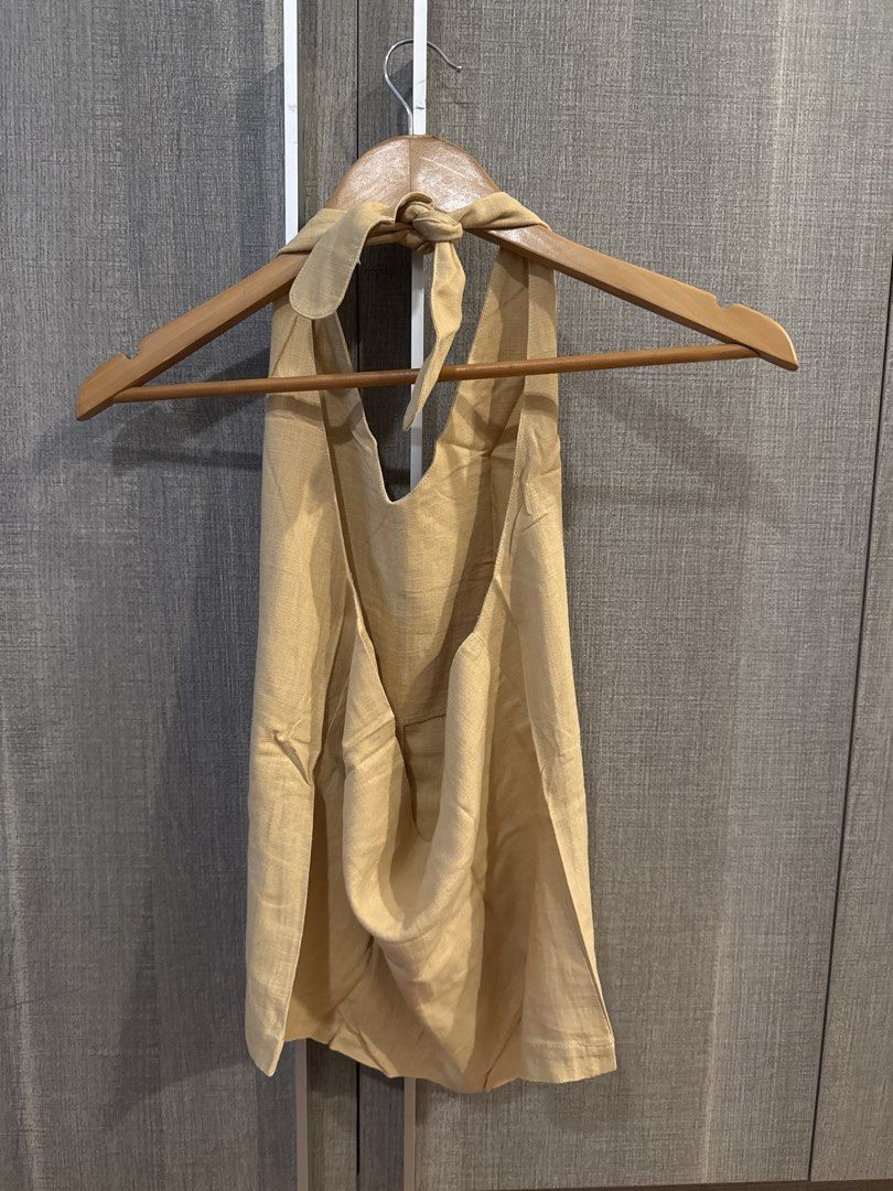 Araw Linen Halter Top (Category: Sleeveless) located in Makati City. Submitted by kkk.shops (Listing ID 1469508877, Image 2). Description: - Design: Halter neck with adjustable tie-back closure and stylish open back - Fabric: Linen - Versatility: Easily pairs with any denim, skirts, or shorts - Condition: Clean and well-maintained.