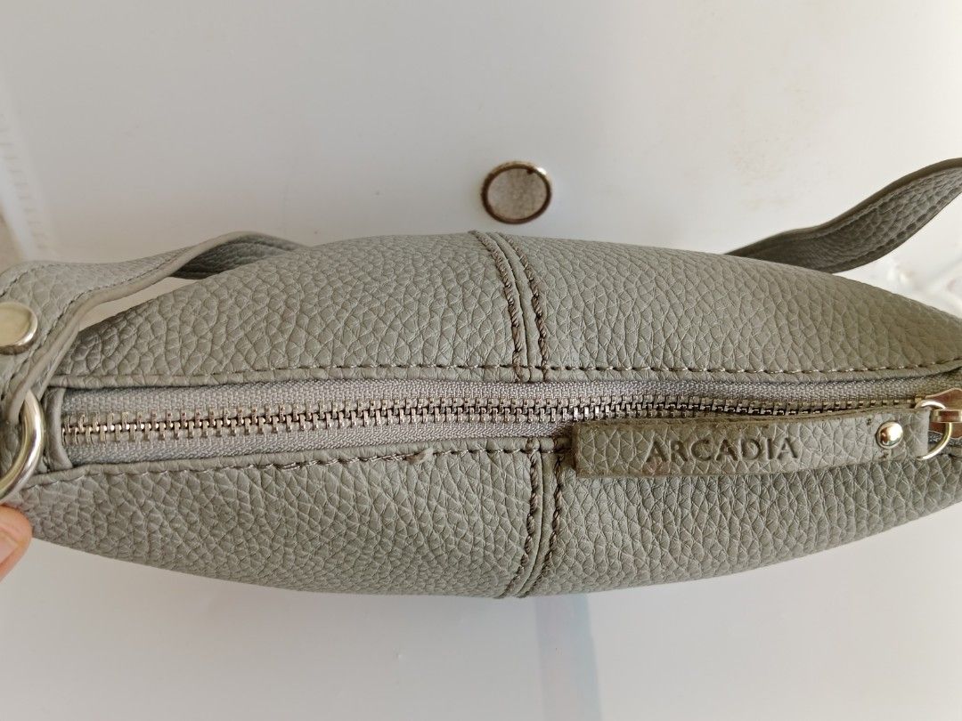 ARCADIA Grey Bucket Bag LD-04GR (Category: Shoulder Bags) located in Manila. Submitted by eze_em8 (Listing ID 1469471401, Image 2). Description: - Brand: ARCADIA - Style: Grey Leather Bag (Model LD-04GR) - Condition: Brand new with product tag attached - Material: Genuine leather exterior with synthetic lining - Dimensions: 24 cm (L) x 14.5 cm (H) x 6.5 cm (W) - Closure: Top zipper with branded leather pull tab - Design details: Stylish vertical 