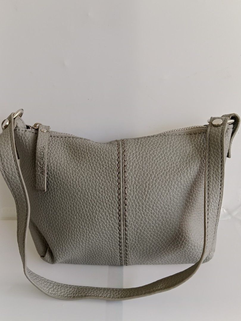 ARCADIA Grey Bucket Bag LD-04GR (Category: Shoulder Bags) located in Manila. Submitted by eze_em8 (Listing ID 1469471401, Image 1). Description: - Brand: ARCADIA - Style: Grey Leather Bag (Model LD-04GR) - Condition: Brand new with product tag attached - Material: Genuine leather exterior with synthetic lining - Dimensions: 24 cm (L) x 14.5 cm (H) x 6.5 cm (W) - Closure: Top zipper with branded leather pull tab - Design details: Stylish vertical 