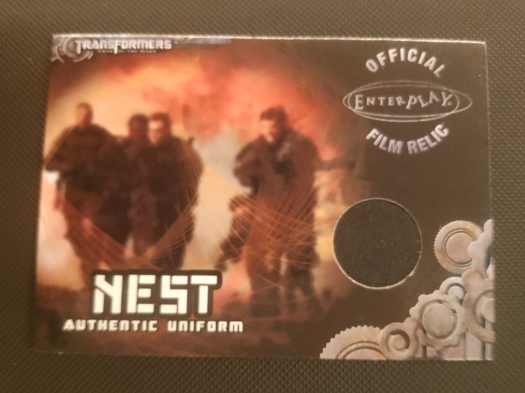 Assorted characters (Category: Raw Singles) located in San Juan City. Submitted by jim.jim7 (Listing ID 1469415041, Image 1). Description: - Authentic Enterplay film relic card from Transformers Revenge of the Fallen - Features a genuine embedded fabric piece from the NEST uniform - Clear, high-quality graphics showcasing soldiers and a fiery background - Detailed gear illustrations featured in the bottom right corner - Official merchandise, perf