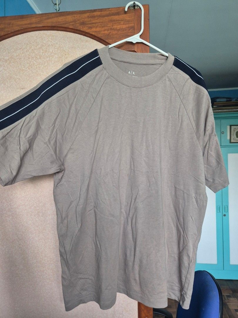 Authentic Armani Exchange Regular Fit T-Shirt Size M (Category: Tshirts & Polo Shirts ) located in Paranaque City. Submitted by monicaboo (Listing ID 1469428726, Image 1). Description: - Brand: Armani Exchange - Fit: Regular fit - Size: Medium (tag printed on inner collar) - Color: Beige / Taupe with contrasting dark navy shoulder stripes - Details: Features A|X logo patch on the shoulders, clean crew neck - Material: Comfortable cotton blend - O