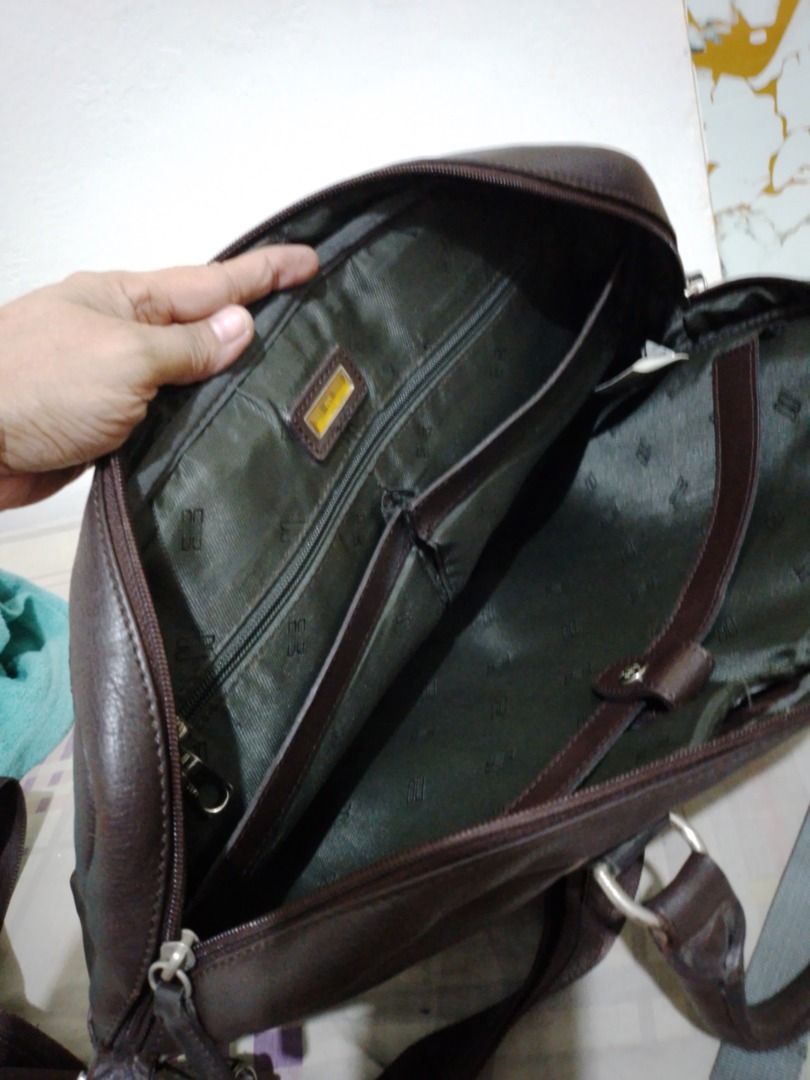 Authentic DAKS Executive Leather Laptop Bag Briefcase with Shoulder Strap (Category: Briefcases) located in Imus. Submitted by bestfinds_yeth0724 (Listing ID 1469570813, Image 3). Description: - Dark brown leather briefcase, ideal for work and daily commutes - Sturdy dual top handles with minor wear from handling - Includes an adjustable canvas shoulder strap - Secure main zip compartment with structured fabric lining - Interior includes a zipper