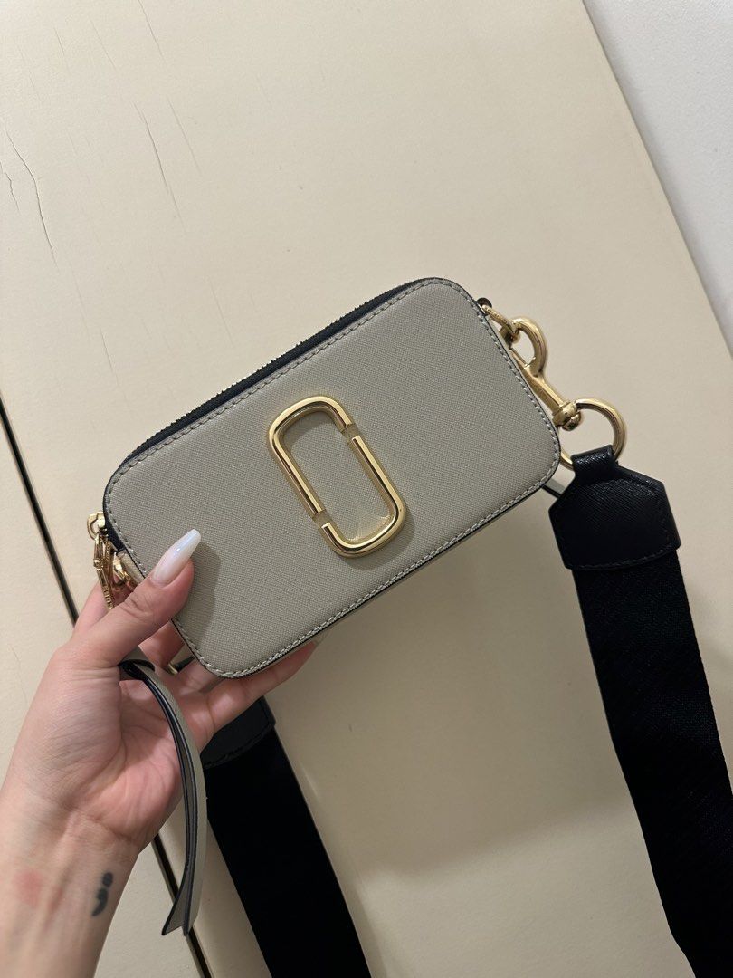 AUTHENTIC Marc Jacobs Snapshot Camera Bag (Category: Luxury Bags & Wallets) located in Rizal. Submitted by yagrlkia (Listing ID 1469563866, Image 1). Description: - Brand: Marc Jacobs Snapshot Camera Bag - Design: Multi-color grey and pink leather panels with gold-tone hardware - Compartments: Double zipped compartments with embossed logo on top - Strap: Interchangeable patterned fabric strap in black, silver, and yellow lettering - Condition: Cl
