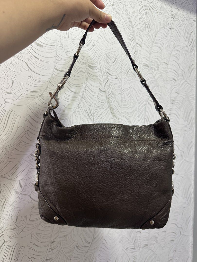 Authentic Preloved Coach Choco Carly Medium Size (Category: Luxury Bags & Wallets) located in Basista. Submitted by glesylbd_22 (Listing ID 1469410897, Image 2). Description: ~ No major flaws, normal signs of use only ~ Hairlines on handle rubberlining but still intact, no cracks - Brand: Coach - Material: Soft pebbled leather in dark brown - Hardware: Silver-tone with metal stud accents on structured corners - Strap: Single shoulder strap with c