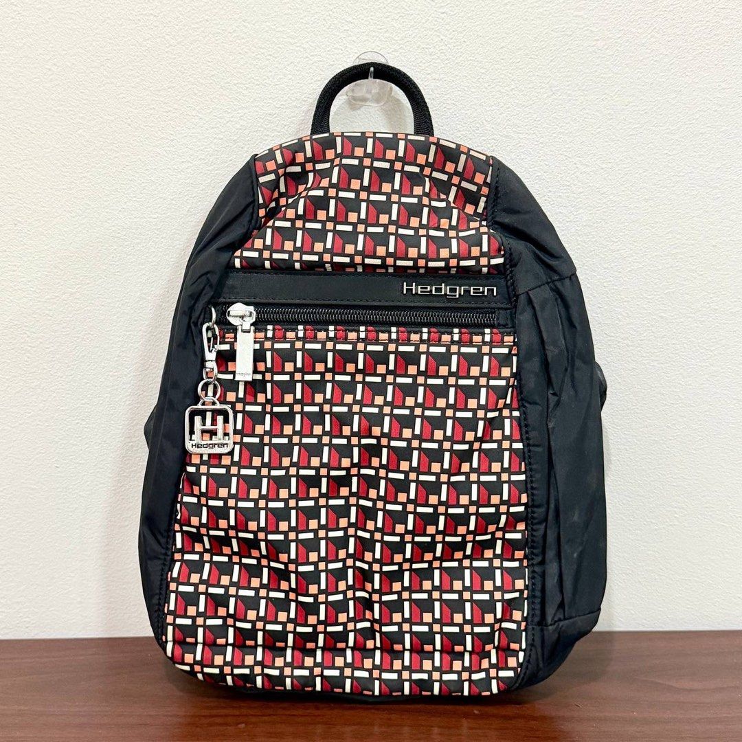 [Authentic] Used Hedgren Black Geometric Print Nylon Backpack Red Orange Pattern Lightweight Bag (Category: Backpacks) located in Quezon City. Submitted by brandedusagoodies (Listing ID 1469553148, Image 1). Description: Used Hedgren backpack featuring a black base with a geometric pattern in red, orange, and cream. It has black side panels, a metallic Hedgren logo and signature keychain charm, a front zippered pocket, and a spacious main compart
