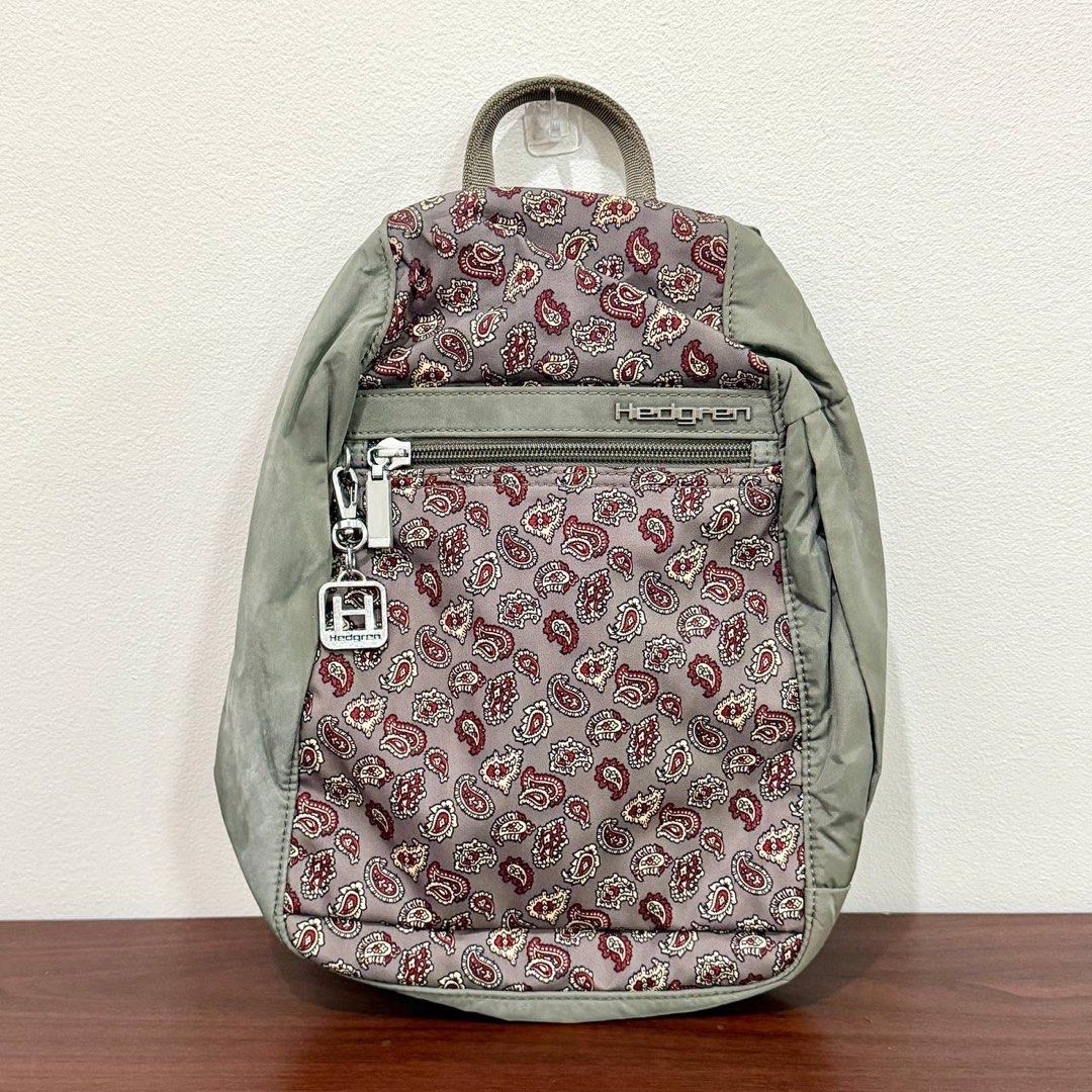 [Authentic] Used Hedgren Gray Paisley Print Nylon Backpack Floral Pattern Lightweight Bag (Category: Backpacks) located in Quezon City. Submitted by brandedusagoodies (Listing ID 1469552322, Image 1). Description: Used Hedgren backpack featuring a gray base with a red, cream, and burgundy paisley print, complemented by muted green panels. It has a front zippered pocket, metallic Hedgren logo and keychain charm, side pockets, adjustable shoulder s