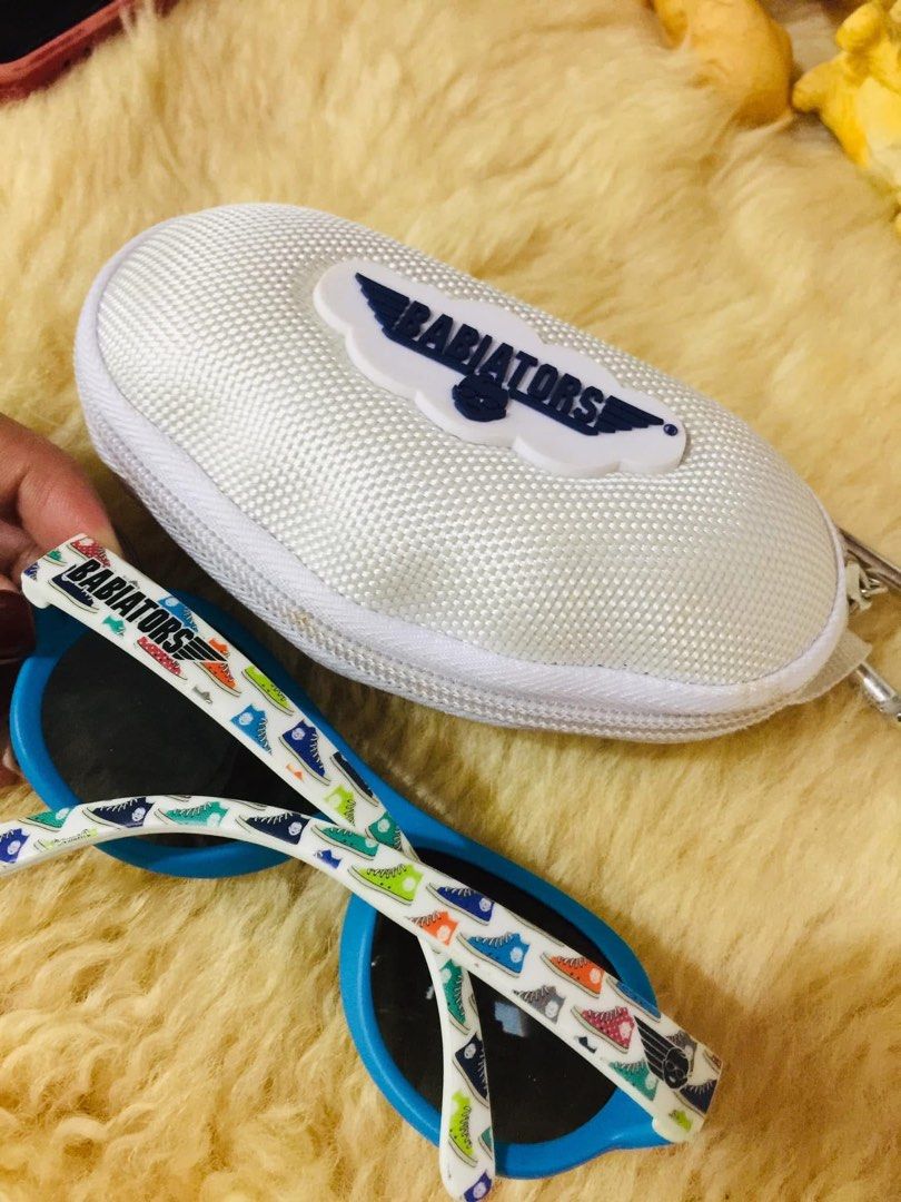 Babiators Kids Sunglasses Ages 3-5 with Case (Category: Babies & Kids Fashion) located in Baguio. Submitted by izza_thrifty (Listing ID 1469567975, Image 3). Description: - Brand: Babiators - Color: Blue and white with fun sneaker pattern on temples - Size: Kids ages 3 to 5 years old - Protection: Dark tinted lenses for reliable sun protection - Inclusion: Matching white hard zipper case with carabiner clip - Ideal for: Outdoor play and sunny day