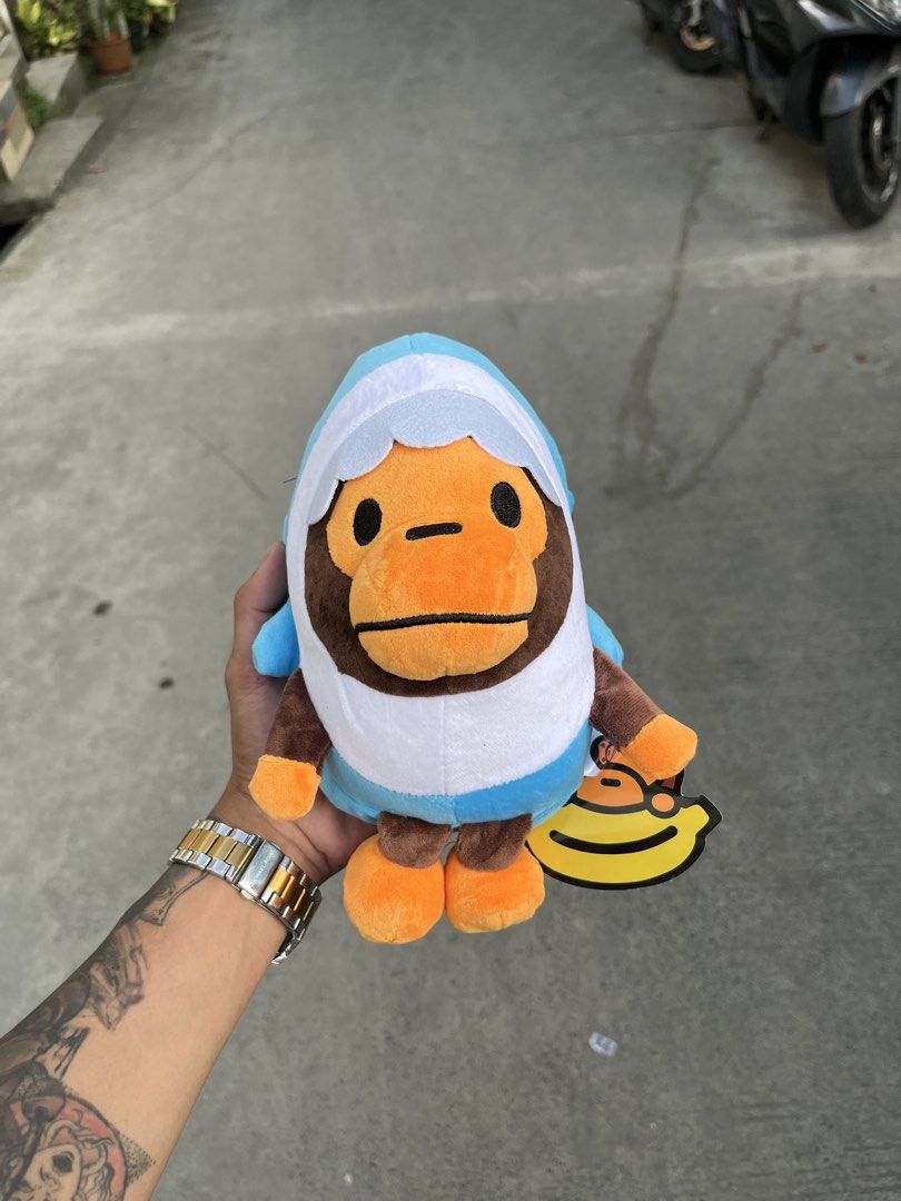 BAPE Baby Milo Plush Toy Collection (Category: Plushies & Soft Toys) located in Manila. Submitted by donthriftph. (Listing ID 1469469024, Image 2). Description: - Set of 4 authentic Baby Milo plush toys - Includes 4 designs: Pink shark hoodie, blue shark hoodie, holding a red heart, and eating a donut - All plushies come with original banana hang tags still attached - Material is ultra-soft, clean, and in pristine condition - Zero stains, flaws, 