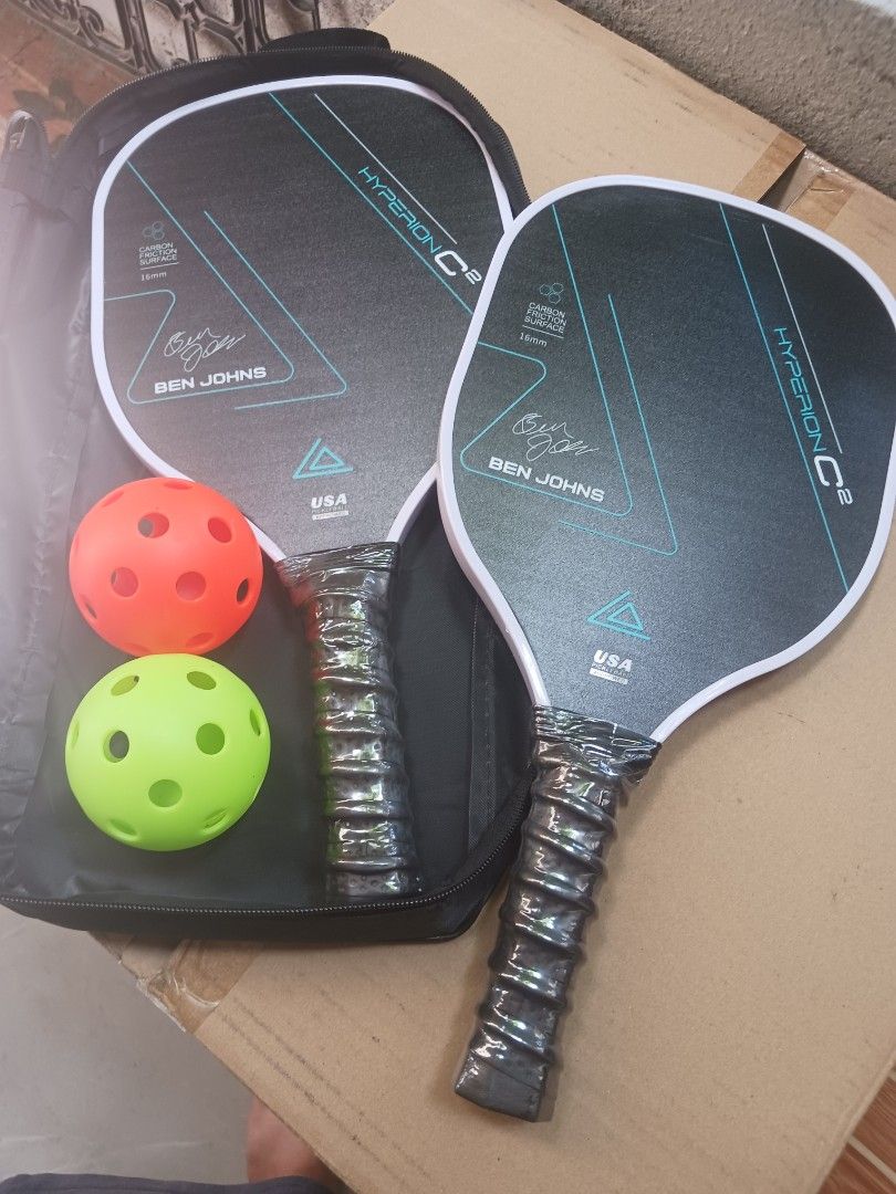 Ben Johns Hyperion C2 Pickleball Paddle (Category: Racket and Ball Sports) located in Cebu City. Submitted by joecristinesayson (Listing ID 1469570542, Image 1). Description: - Model: Ben Johns Hyperion C2 - Surface & Core: Carbon friction surface, 16mm thickness - Certification: USA Pickleball approved stamp - Condition: Brand new, handle still wrapped in original plastic - Inclusions: Includes two pickleballs and a carrying case - Status: Game-