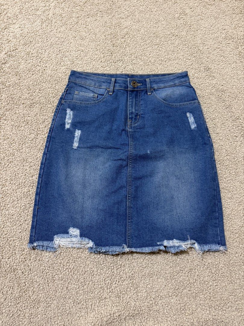 Bench OJ Distressed Denim Skirt (Category: Skirts) located in Las Pinas. Submitted by ann.co. (Listing ID 1469542094, Image 1). Description: - Brand: Bench OJ - Wash: Medium blue with distressed front/back pockets - Details: Raw frayed hem, red leather brand patch, and back slit for easy movement - Closure: Button closure with zip fly and belt loops - Condition: Excellent, classic everyday piece.