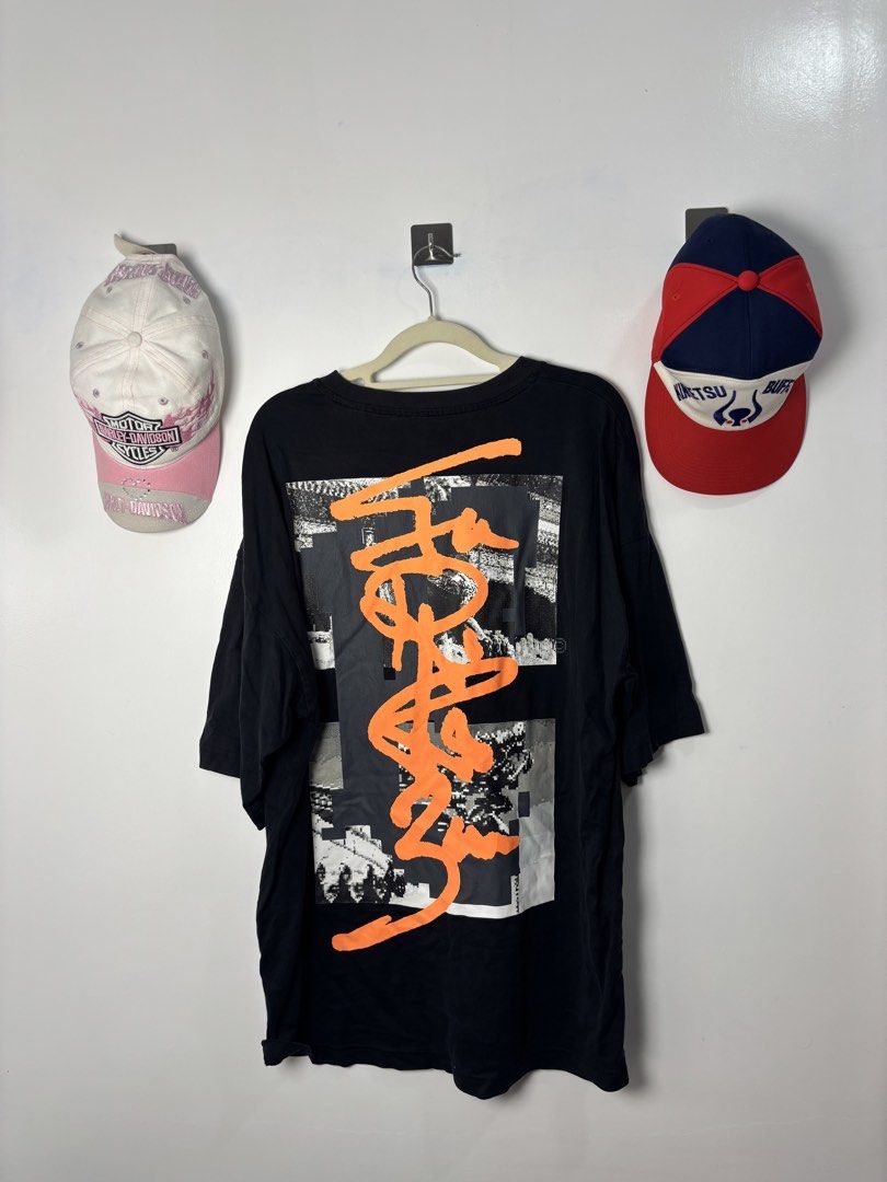 Black Graphic Oversized T-Shirt Orange Print (Category: Tshirts & Polo Shirts ) located in Calbayog City. Submitted by zaxcheus_castillo1708 (Listing ID 1469523625, Image 2). Description: - Color: Black - Fit: Oversized with relaxed drop shoulders - Design: Orange graphic text on front chest; large collage graphic with orange graffiti lettering on the back - Details: Round neckline and small woven label tag near the bottom right hem - Style: Stre