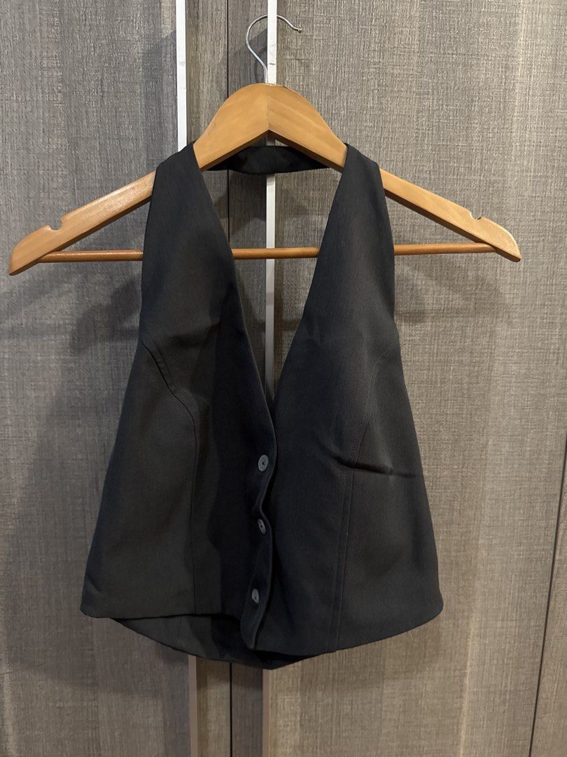Black Halter Top Vest Front Button Up (Category: Sleeveless) located in Makati City. Submitted by kkk.shops (Listing ID 1469511912, Image 1). Description: - Color: Solid black - Style: Halter neck, sleeveless, open back - Fit: Tailored bodice with a stylish pointed hem - Details: Functional button-up front - Versatility: Easily pairs with denim jeans for casual days or trousers for a dressed-up look.