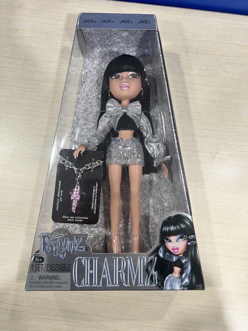 Bratz Charmz Jade Doll Unopened Box (Category: Kids Toys) located in Manila. Submitted by happydays.com (Listing ID 1469421143, Image 2). Description: - Brand: Bratz (Charmz Series - Jade) - Condition: Brand new, never removed from box (NRFB), crisp corners - Hair: Long black hair with signature bangs - Outfit: Metallic silver top, sparkly skirt, and matching heels - Accessories: Includes a chain necklace with a pink charm - Packaging: Clear fron