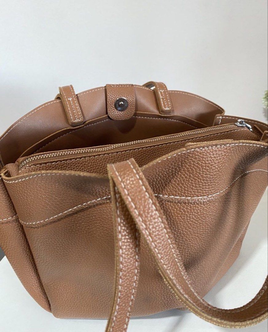 Brown dumpling bag (Category: Tote Bags) located in Manila. Submitted by pattydeclutters (Listing ID 1469411540, Image 1). Description: Material: Premium brown pebbled leather with stylish white contrast stitching Straps: Dual top carry handles and longer shoulder straps Closure: Secure magnetic snap Interior: Features a zippered middle compartment divider and convenient open side pockets Condition: 10/10 RFS: too many bags.