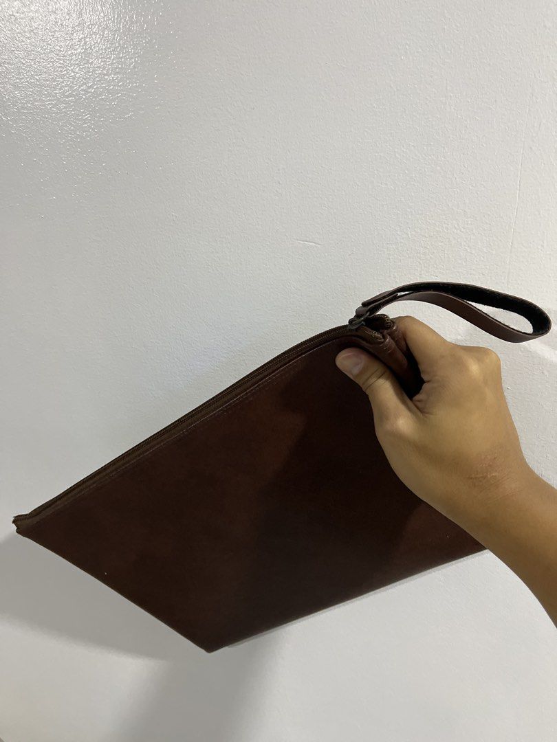 Brown Leather Clutch Bag with Wrist Strap (Category: Clutches) located in Manila. Submitted by curated.clutter12 (Listing ID 1469516675, Image 2). Description: - Color: Dark brown - Material: Smooth faux leather with a subtle grain pattern - Closure: Secure top zipper - Features: Attached side wrist strap, clean interior lining - Capacity: Slim profile, perfect for phone, cards, and keys - Style: Grab-and-go everyday clutch.