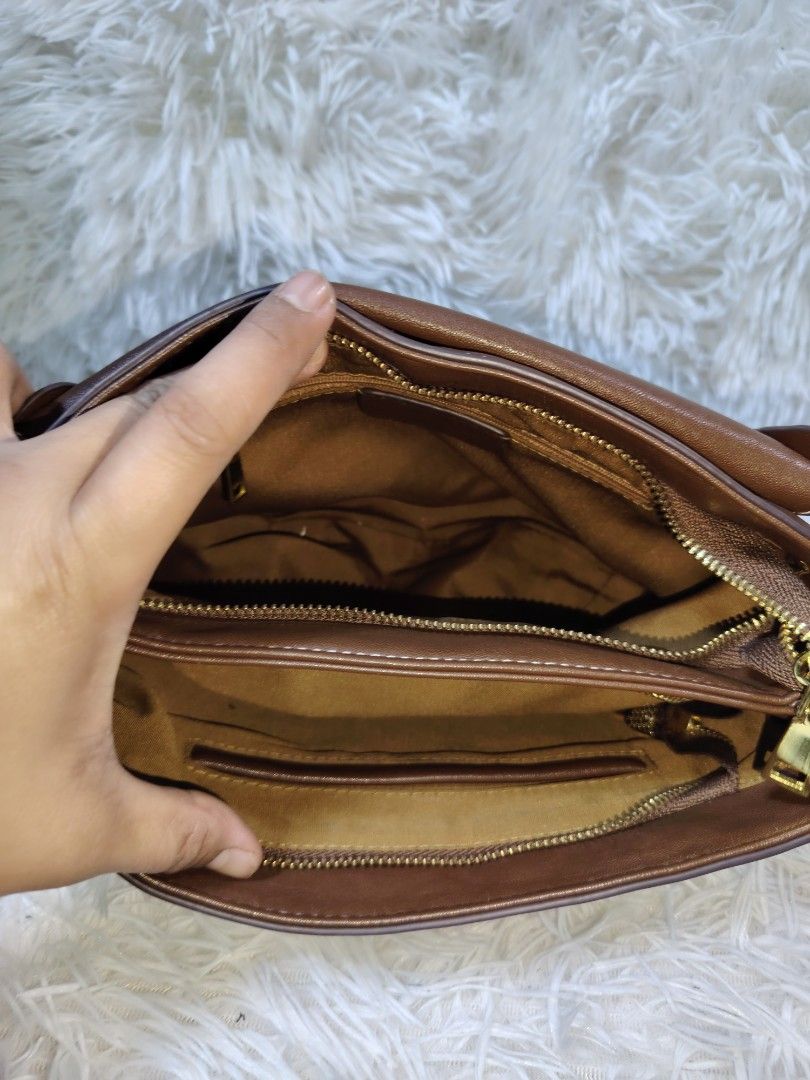 Brown Leather Crossbody Bag with Flap Closure (Category: Cross-body Bags) located in Quezon City. Submitted by zhelcloset01 (Listing ID 1469506044, Image 3). Description: - Material: Genuine brown leather with stylish white contrast stitching - Design: Unique curved bottom shape with a secure front flap and vertical lighter brown strap - Hardware: Premium gold-tone metal clasps - Strap: Adjustable matching shoulder strap for comfortable wear - In