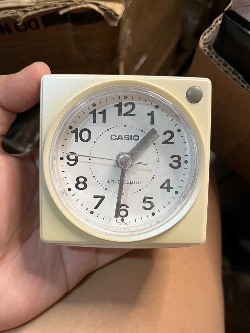Casio Wave Ceptor TQ-750J Analog Alarm Clock (Category: Clocks) located in Gapan. Submitted by lunashop14 (Listing ID 1469398867, Image 1). Description: - Brand: Casio Wave Ceptor - Color/Material: Off-white plastic casing - Design: Square shape with round analog dial, black numerals, and luminous hands - Controls: Rear time setting, set, reset, and wave buttons, with a side on/off switch - Power: Uses 1 AA battery - Condition: Tested, working gr