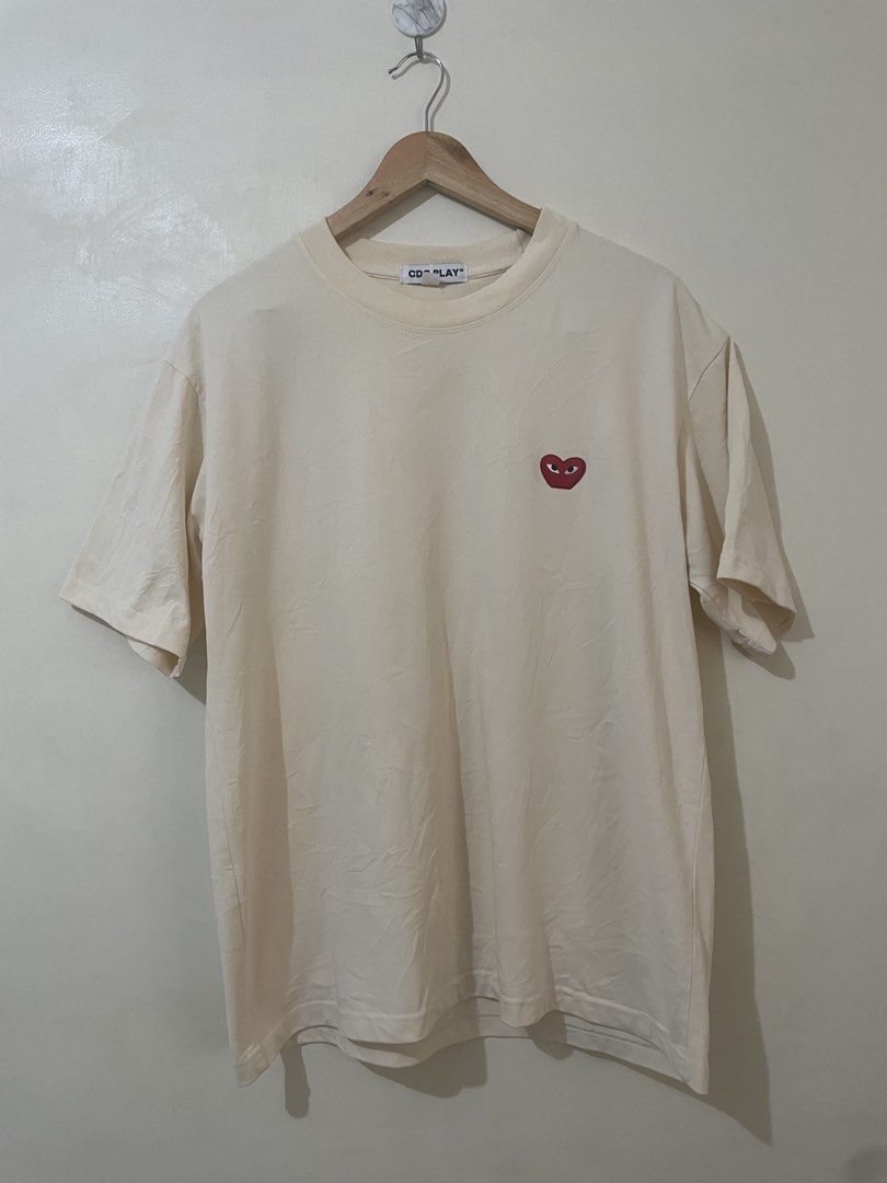 CDG PLAY Heart Logo Tee Cream Size L (Category: Activewear) located in Davao. Submitted by thegraildept2026 (Listing ID 1469415744, Image 1). Description: - Brand: Comme des Garçons PLAY - Color: Soft cream - Size: L (170/88A) - Design: Embroidered red heart logo patch on chest - Material: Comfortable cotton jersey - Condition: Clean collar tag, great basic piece for everyday wear.