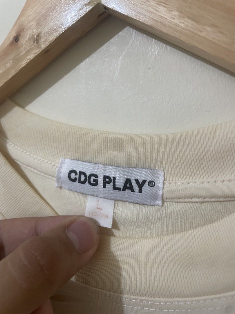CDG PLAY Heart Logo Tee Cream Size L (Category: Activewear) located in Davao. Submitted by thegraildept2026 (Listing ID 1469415744, Image 3). Description: - Brand: Comme des Garçons PLAY - Color: Soft cream - Size: L (170/88A) - Design: Embroidered red heart logo patch on chest - Material: Comfortable cotton jersey - Condition: Clean collar tag, great basic piece for everyday wear.