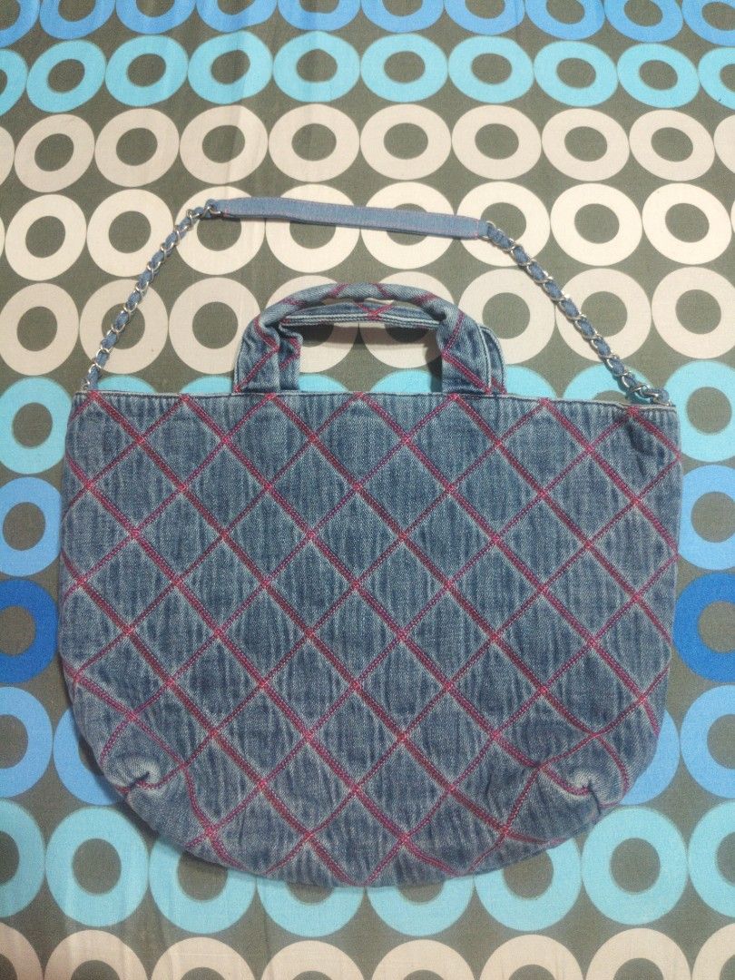 Chanel Denim Quilted Tote Bag with Chain Strap (Category: Tote Bags) located in San Mateo. Submitted by roxyj120919 (Listing ID 1469488308, Image 2). Description: Blue denim tote bag with pink diamond stitching all over. Silver interlocking CC logo plate on the front with serial number KCNL6P55. Dual denim top handles and a chain-interwoven shoulder strap. Front slip pocket matching the quilted design. Metal plaque inside stamped Chanel Paris. Ov