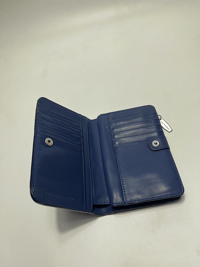 Charles & Keith Blue Wallet (Category: Wallets & Card holders) located in Iloilo. Submitted by fromthebins.ilo2 (Listing ID 1469464171, Image 3). Description: - Brand/Model: Charles & Keith Wallet - Color: Navy blue - Material: Textured leather finish - Closure: Secure snap button on main flap - Interior: Multiple card slots on both sides and clean blue lining - Compartments: Separate zippered pocket for coins and folded cash - Design: Compact si