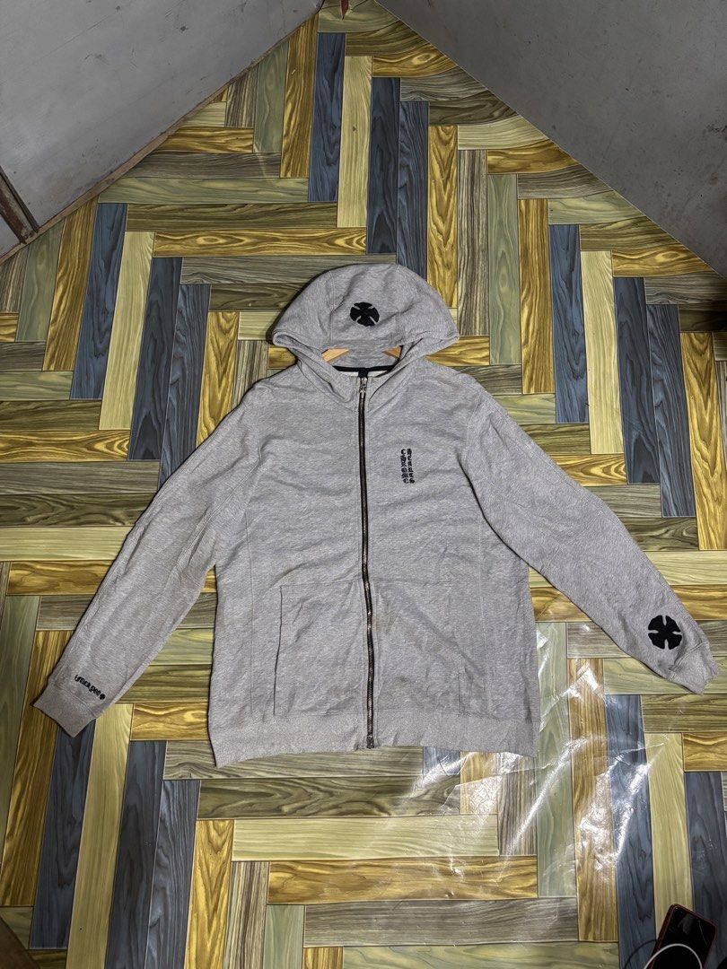 Chrome Hearts Grey Zip-Up Hoodie (Category: Hoodies) located in Manila. Submitted by thriftkibs (Listing ID 1469558459, Image 1). Description: - Brand: Chrome Hearts - Style: Grey cotton zip-up hoodie, casual streetwear staple - Details: Black cross patch on hood and left sleeve, vertical printed text branding on chest - Hardware: Signature dagger zipper pull - Fit: Ribbed cuffs and hem - Condition: Good, with some minor discoloration around the 