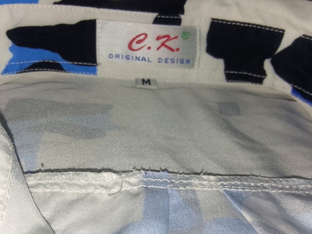 C.K Sleeves (Category: Coats, Jackets and Outerwear) located in Roxas City. Submitted by xanshopz.5800 (Listing ID 1469409271, Image 3). Description: 📝 Product Description Item: Men's Short-Sleeve Printed Shirt Brand: C.K. — Original Design Size: Medium (M) Colorway: Off white base with bright blue and bold black abstract lettering graffiti style print Cut: Relaxed, casual fit, standard collar, button-front placket, short sleeves Style: Modern s