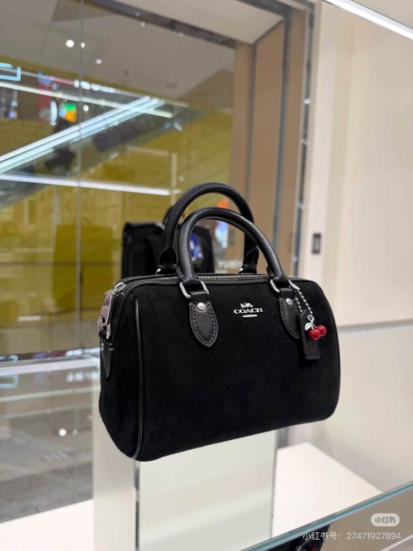 Coach Black Suede Mini Rowan Satchel (Category: Luxury Bags & Wallets) located in Rizal. Submitted by vanbdc24 (Listing ID 1469508739, Image 3). Description: - Brand: Coach - Style: Mini satchel bag - Material: Black suede with smooth leather trim - Hardware: Silver-tone - Closure: Top zip closure with dual grab handles - Strap: Includes a detachable crossbody strap - Interior: Clean black fabric lining - Extra: Playful red cherry charm included 