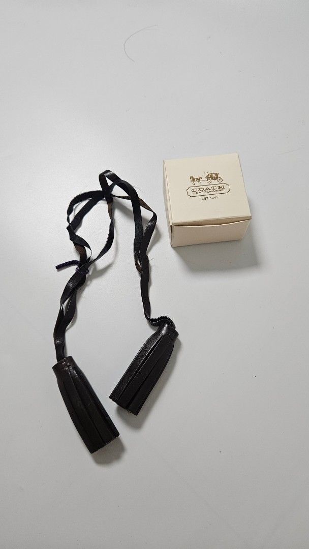 Coach Leather Tassel Bag Charm (Category: Wallets & Card holders) located in Alfonso. Submitted by jbcamet (Listing ID 1469516041, Image 1). Description: - Brand: Genuine Coach Leatherware - Color: Dark brown - Inclusions: Original beige box included - Features: Long straps, classic design, and high-quality finish - Perfect for: Upgrading and styling plain tote or shoulder bags.