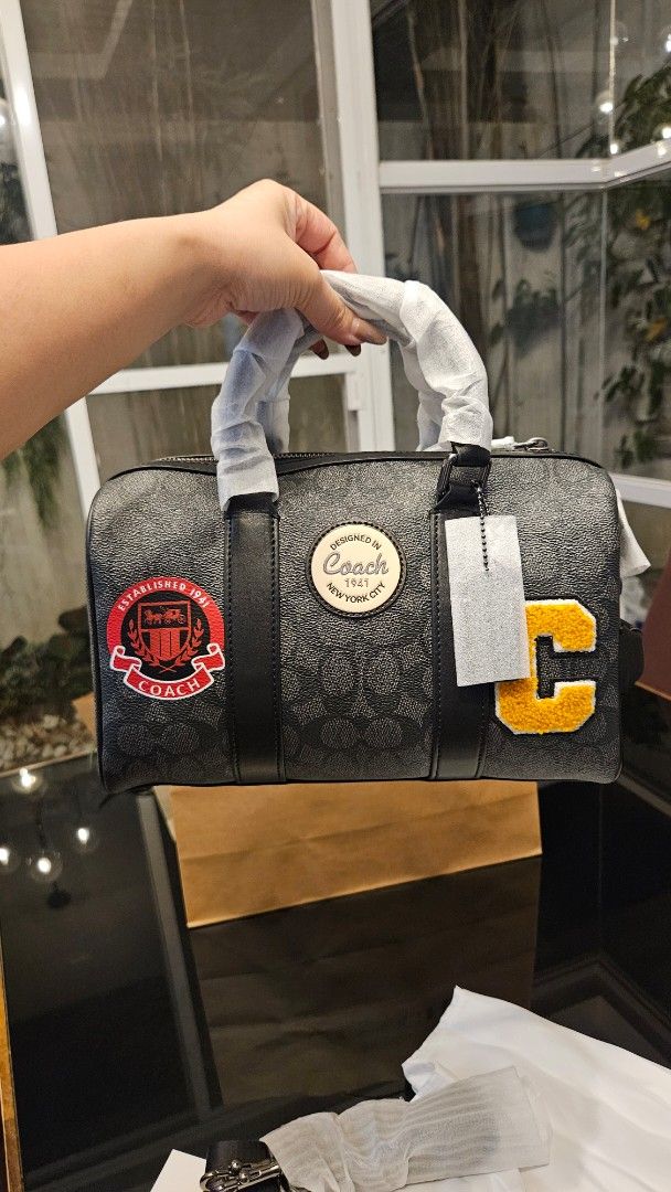 Coach Venturer (Category: Luxury Bags & Wallets) located in Rizal. Submitted by vanbdc24 (Listing ID 1469505301, Image 1). Description: - Authentic Coach Boston Bag in charcoal signature canvas - Black leather trim, dual top zip closure, and detachable shoulder strap - Features stylish yellow chenille letter C and red varsity shield patches with round Coach logo - Includes original dust bag and paper bag - Meet-ups and same-day delivery available