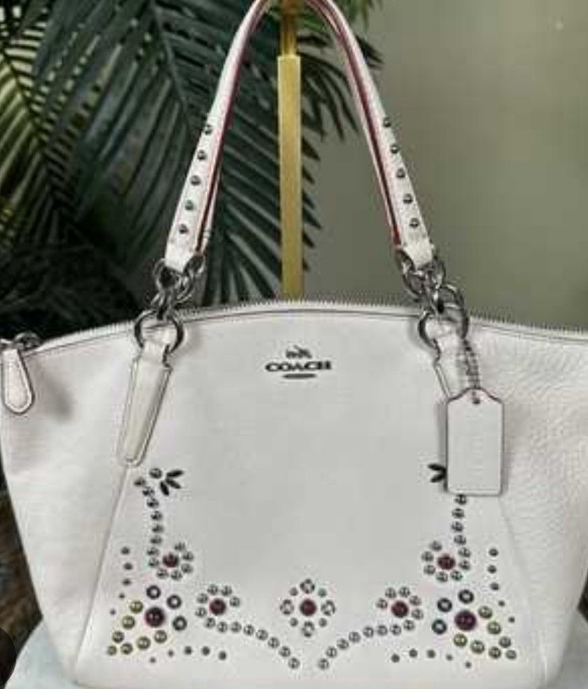 Coach White Leather Studded Floral Handbag (Category: Cross-body Bags) located in Manila. Submitted by lene48 (Listing ID 1469509183, Image 1). Description: - Brand: Coach - Material: Premium pebbled white leather - Hardware: Silver-tone - Design: Detailed studded floral pattern on the lower front - Closure: Secure zip top - Carry Options: Double top handles and an adjustable, detachable shoulder strap - Extras: Includes original leather hang tag