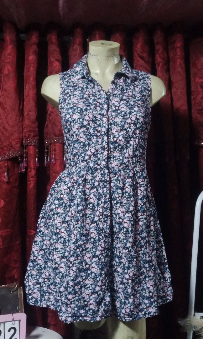 Cotton mini dress (Category: Dresses) located in Manila. Submitted by wheneity67thifted (Listing ID 1469563482, Image 2). Description: This is a sleeveless, button-down mini-length shirt dress featuring an all-over small pink and white floral print against a dark or navy-black background, complete with a classic collar and a flared, pleated skirt..