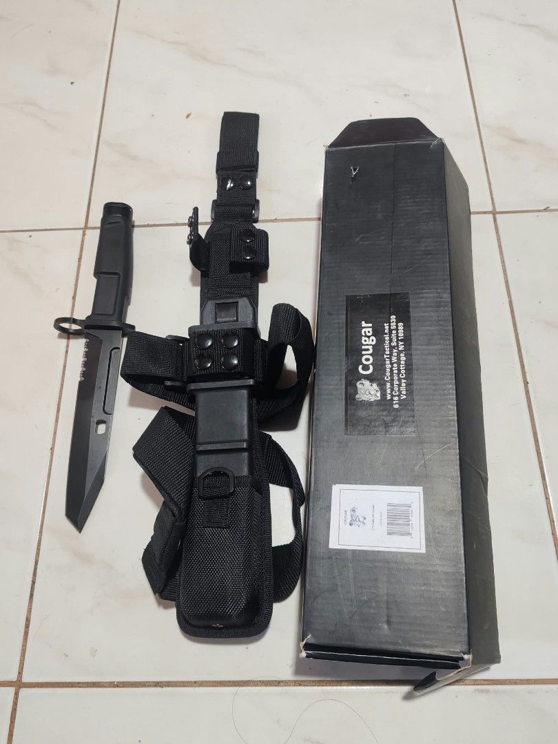 Cougar Tactical with Sheath and Box (Category: Hiking & Camping) located in Bacoor. Submitted by kuroochiii94695 (Listing ID 1469401600, Image 1). Description: - Brand: Cougar tactical kn i f e - Finish: Matte black with serrated spine - Handle: Rugged design with integrated guard - Sheath: Heavy-duty black nylon with multiple straps, belt loops, and modular attachments - Inclusions: Original Cougar-branded box with barcode - Condition: Sturdy, h