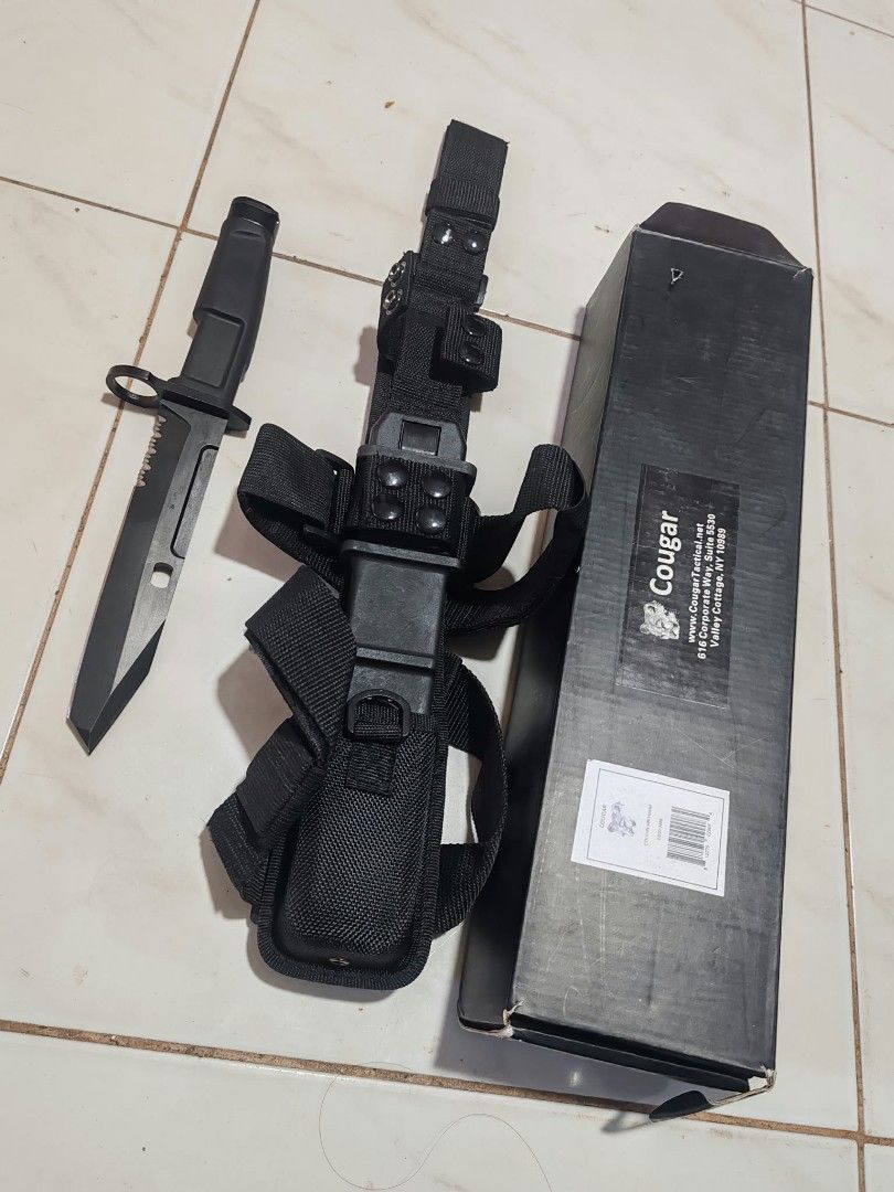 Cougar Tactical with Sheath and Box (Category: Hiking & Camping) located in Bacoor. Submitted by kuroochiii94695 (Listing ID 1469401600, Image 2). Description: - Brand: Cougar tactical kn i f e - Finish: Matte black with serrated spine - Handle: Rugged design with integrated guard - Sheath: Heavy-duty black nylon with multiple straps, belt loops, and modular attachments - Inclusions: Original Cougar-branded box with barcode - Condition: Sturdy, h