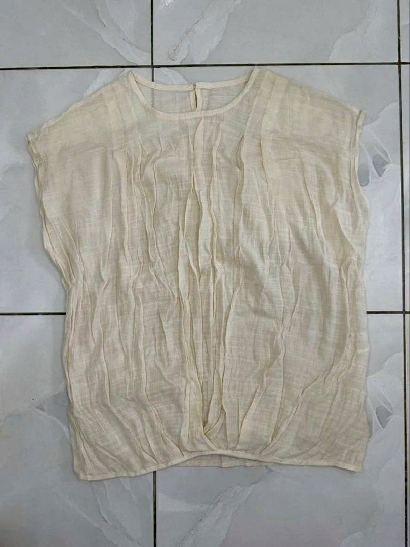 Cream pleated front short sleeve blouse (Category: Blouses) located in Cagayan de Oro. Submitted by ninaaam (Listing ID 1469430129, Image 1). Description: - Color: Cream - Style: Short sleeve top with round neckline - Design: Pleated texture on front panel with a gathered, draped hem - Material: Lightweight and comfortable - Versatility: Easy to pair with pants or skirts for casual wear.