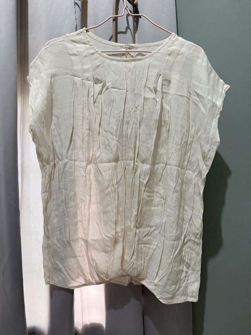 Cream pleated front short sleeve blouse (Category: Blouses) located in Cagayan de Oro. Submitted by ninaaam (Listing ID 1469430129, Image 2). Description: - Color: Cream - Style: Short sleeve top with round neckline - Design: Pleated texture on front panel with a gathered, draped hem - Material: Lightweight and comfortable - Versatility: Easy to pair with pants or skirts for casual wear.