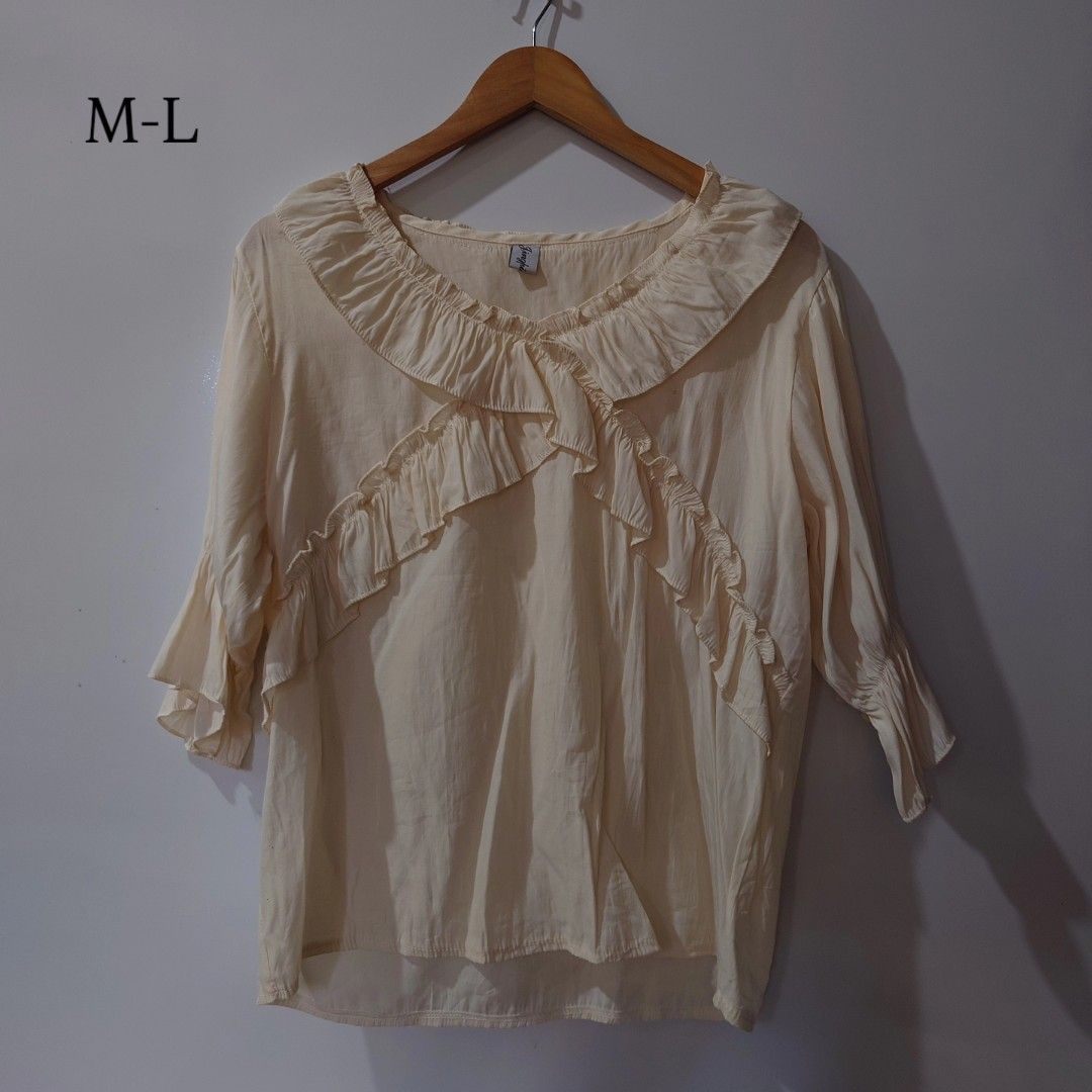 Cream Ruffled Blouse Size M-L (Category: Blouses) located in Diffun. Submitted by declutteredbyJill (Listing ID 1469570099, Image 1). Description: - Color: Cream - Size: Fits Medium to Large - Design: Playful ruffled neckline with a chic crossover front - Sleeves: 3/4 length with matching ruffle cuffs - Fit: Relaxed, lightweight, and comfortable - Styling: Versatile piece that pairs easily with skirts or trousers.