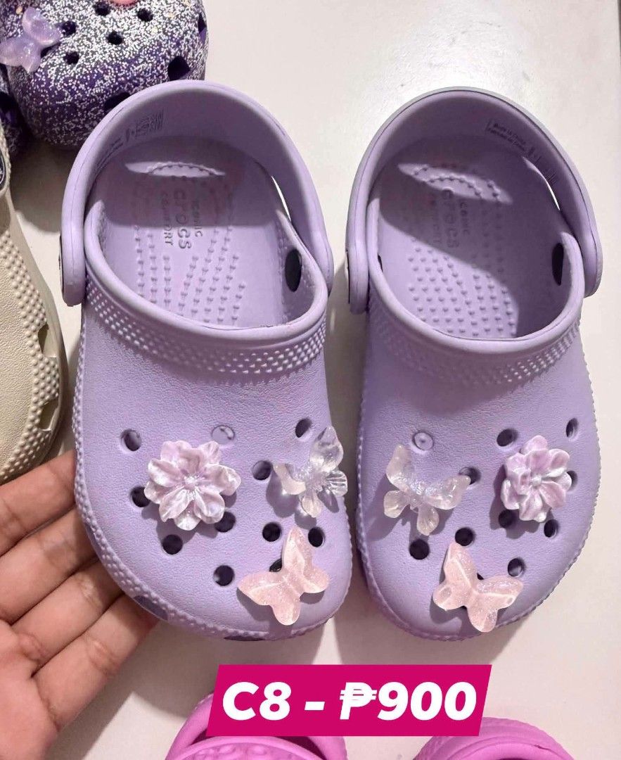 Crocs C8 Purple Kids Clogs with Jibbitz (Category: Babies & Kids Fashion) located in San Fabian. Submitted by hbrst1998 (Listing ID 1469487668, Image 1). Description: - Size: C8 - Color: Purple - Design: Pre-decorated with adorable butterfly and flower charms on both shoes - Comfort: Features Iconic Comfort footbed - Style: Easy slip-on style - Condition: Clean, well-maintained.