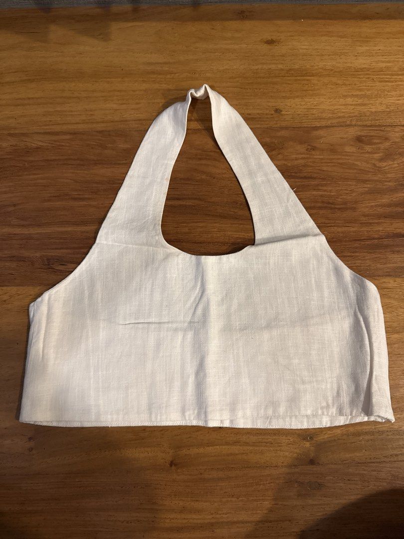 Cropped Linen Halter Top (Category: Sleeveless) located in Makati City. Submitted by kkk.shops (Listing ID 1469508576, Image 1). Description: - Color: Off white - Style: Cropped halter top with open back - Material: Linen - Design: Thick neck strap for comfortable support - Pairing: Great with high-waisted shorts or skirts for warm weather - Condition: Brand new and ready to wear.