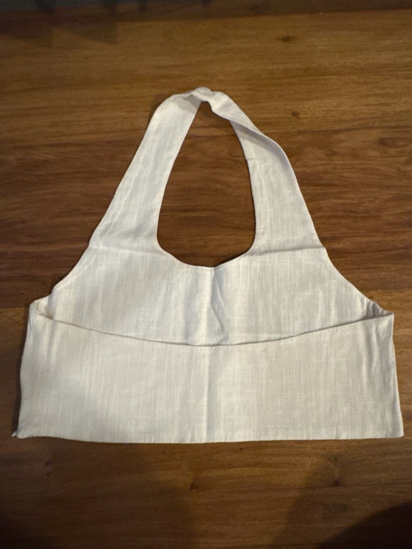 Cropped Linen Halter Top (Category: Sleeveless) located in Makati City. Submitted by kkk.shops (Listing ID 1469508576, Image 2). Description: - Color: Off white - Style: Cropped halter top with open back - Material: Linen - Design: Thick neck strap for comfortable support - Pairing: Great with high-waisted shorts or skirts for warm weather - Condition: Brand new and ready to wear.