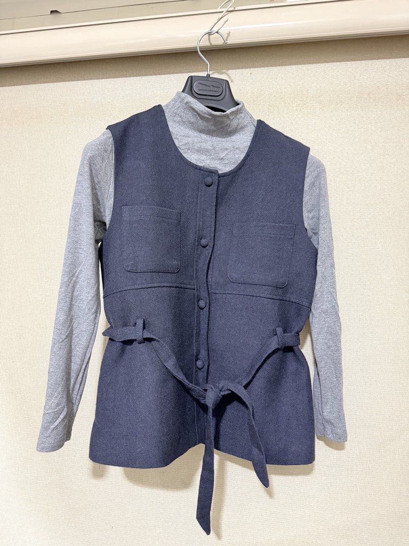 Dark Blue Button-Up Vest with Belt (Category: Sleeveless) located in Cavite. Submitted by mgd.blessed (Listing ID 1469436166, Image 2). Description: - bought in Taiwan - Style: Dark blue sleeveless vest layered over a grey turtleneck top - Details: Functional front fabric buttons and dual chest pockets - Fit: Includes a matching waist tie belt for an adjustable, flattering silhouette - Material: Structured and clean fabric - Condition: Excellent 