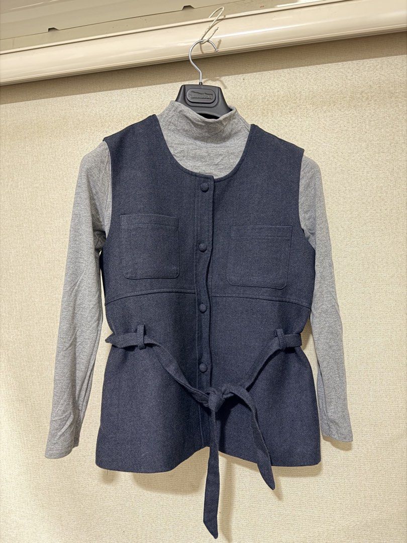 Dark Blue Button-Up Vest with Belt (Category: Sleeveless) located in Cavite. Submitted by mgd.blessed (Listing ID 1469436166, Image 1). Description: - bought in Taiwan - Style: Dark blue sleeveless vest layered over a grey turtleneck top - Details: Functional front fabric buttons and dual chest pockets - Fit: Includes a matching waist tie belt for an adjustable, flattering silhouette - Material: Structured and clean fabric - Condition: Excellent 