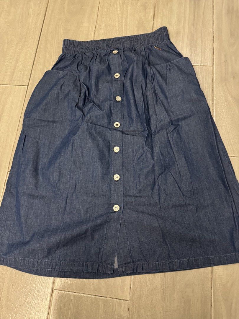 Denim Skirt with Front Buttons and Pockets (Category: Skirts) located in Taguig. Submitted by sqaumejada (Listing ID 1469416389, Image 1). Description: - Color: Dark blue denim - Length: Standard midi / knee-length - Waist: Elastic at the back for a comfortable fit - Details: Full row of white buttons in front, front hem slit - Pockets: Two deep side pockets - Material: Soft and durable denim, clean stitching throughout - Styling: Easy to pair wi